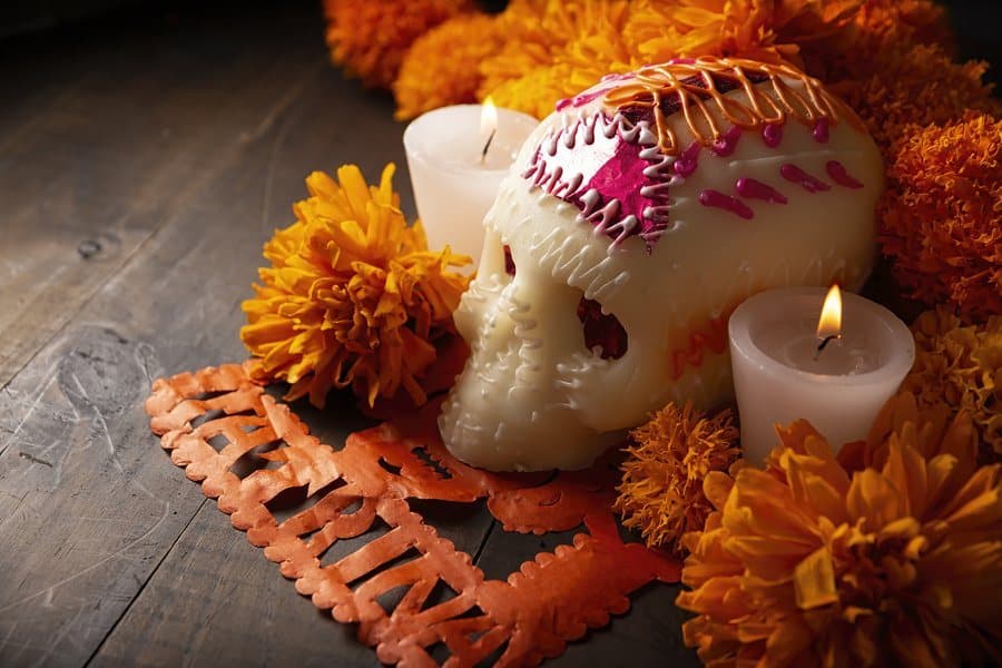 Cempasúchil, candles and papel picado around a sugar skull