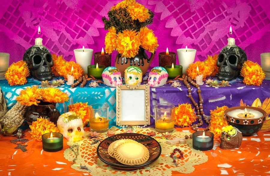 An ofrenda with cempasúchil, candles, skulls and papel picado